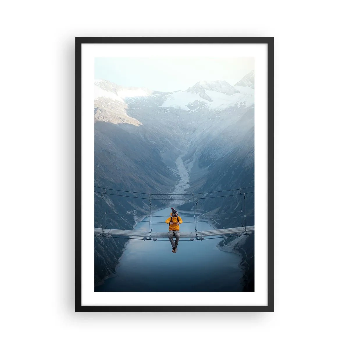 Plakat i sort ramme - En person i en gul jakke sidder på en hængebro over en dal - 50x70cm - Glad for suspension - Moderne vægdekoration til stue og soveværelse ARTTOR