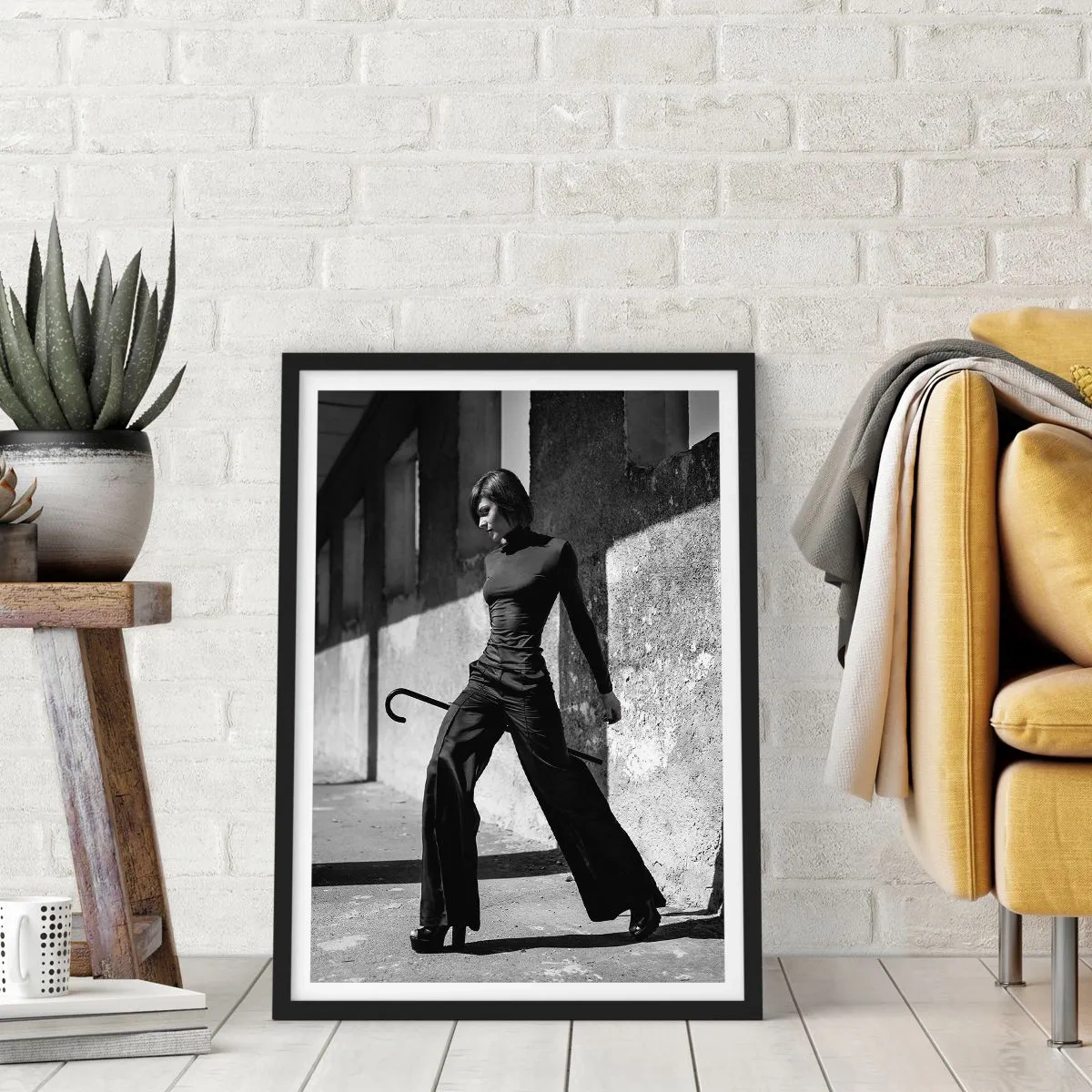 Plakat i sort ramme - En kvinde i et elegant outfit med en stok mod en baggrund af barsk arkitektur - 50x70cm - Byens elegance - Moderne vægdekoration til stue og soveværelse ARTTOR