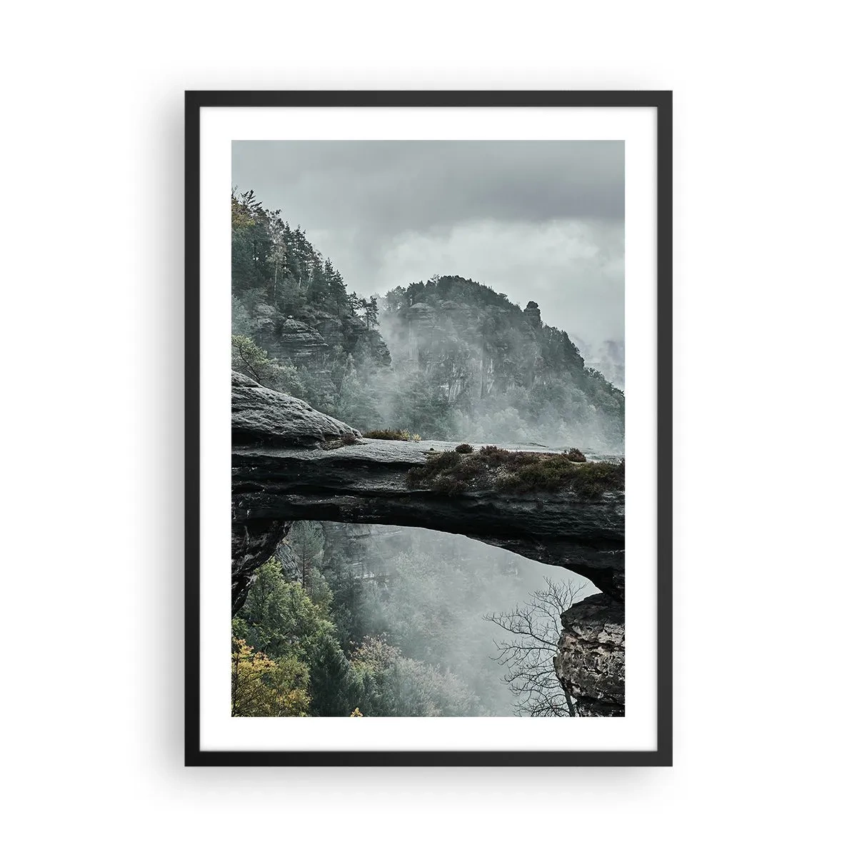 Plakat i sort ramme - Et fotografi af en mystisk klippebro indhyllet i tåge i et bjerglandskab. - 50x70cm - Eventyret er ved at begynde - Moderne vægdekoration til stue og soveværelse ARTTOR