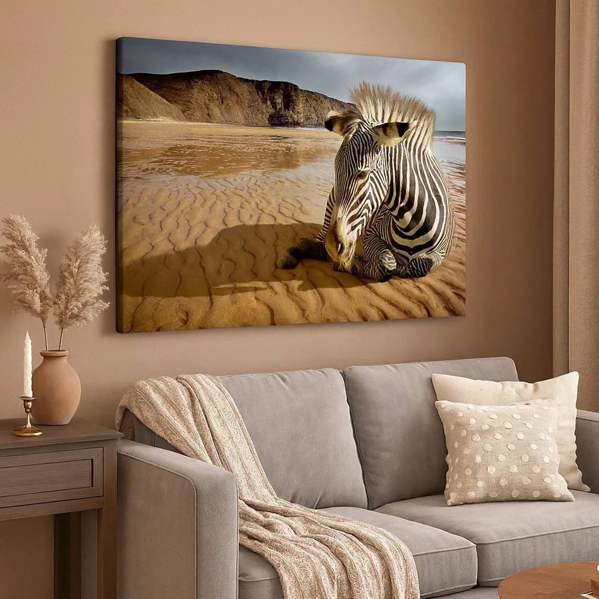 Lærredstryk - Billede på lærred - En zebra hviler på en sandstrand med klipper i baggrunden. - 70x50cm - Vi passer sammen - Moderne vægdekoration til stue og soveværelse ARTTOR