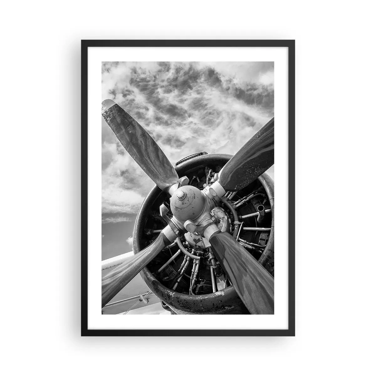Plakat i sort ramme - Et sort-hvidt fotografi af en flypropel mod himlen. - 50x70cm - Himmelens erobrer - Moderne vægdekoration til stue og soveværelse ARTTOR