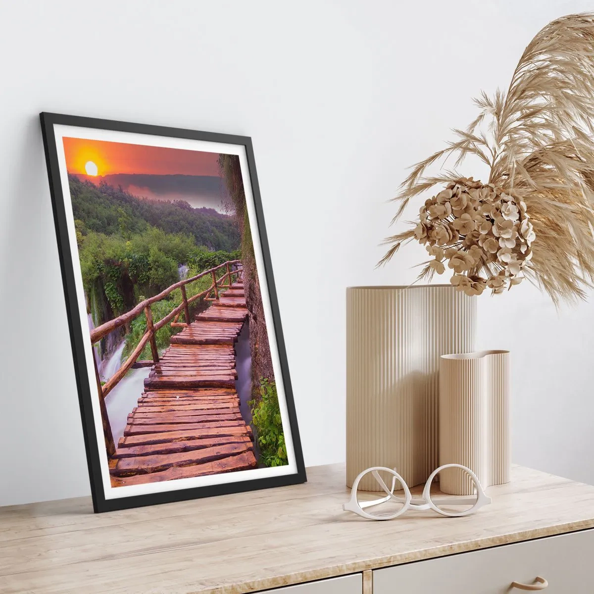 Plakat i sort ramme - En træbro blandt grønne områder og den nedgående sol - 50x70cm - En utrolig skønhed - Moderne vægdekoration til stue og soveværelse ARTTOR