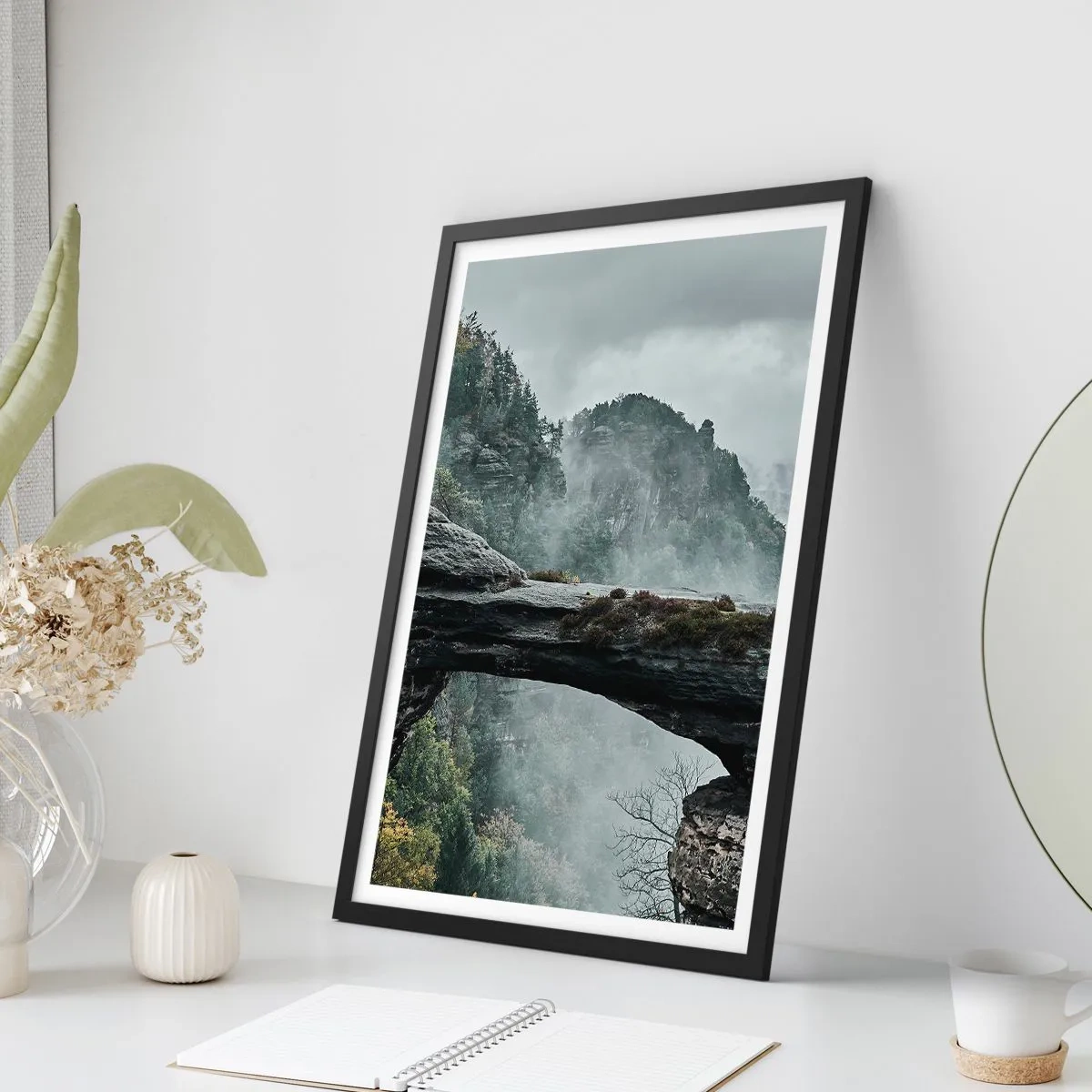 Plakat i sort ramme - Et fotografi af en mystisk klippebro indhyllet i tåge i et bjerglandskab. - 50x70cm - Eventyret er ved at begynde - Moderne vægdekoration til stue og soveværelse ARTTOR