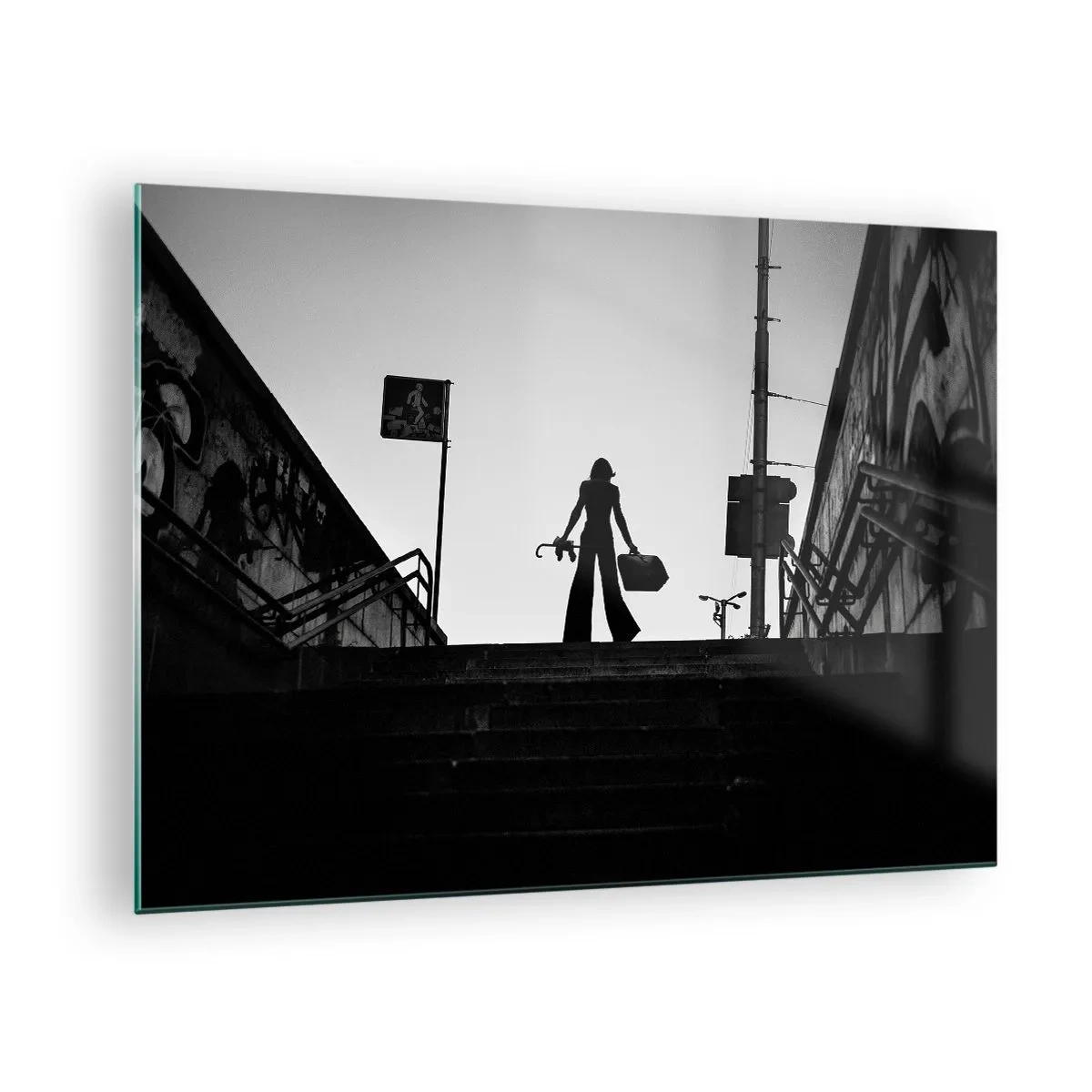 Billede på glas - Sort-hvid silhuet af en kvinde mod en bylandskabs baggrund - 70x50cm - Vandring i byen - Moderne vægdekoration til stue og soveværelse ARTTOR