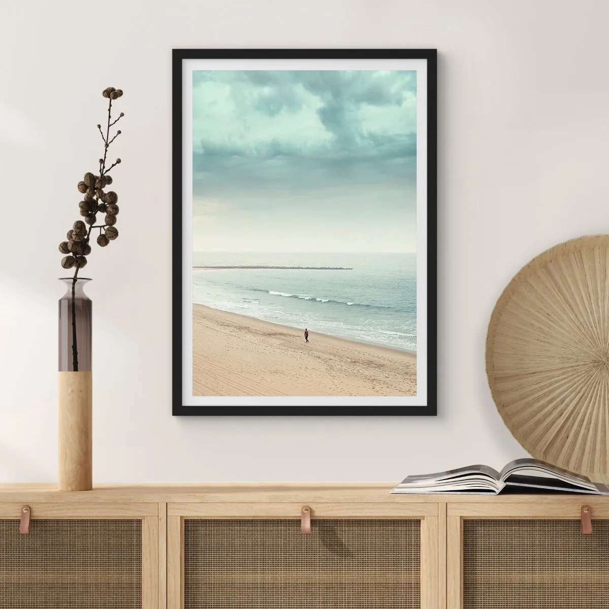 Plakat i sort ramme - En ensom skikkelse går langs kysten under en overskyet himmel. - 50x70cm - På jagt efter fred - Moderne vægdekoration til stue og soveværelse ARTTOR