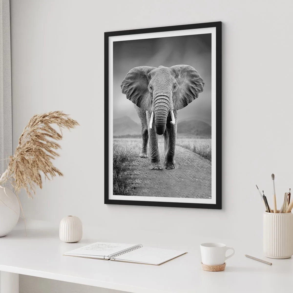 Plakat i sort ramme - En elefant mod et afrikansk landskab i sort-hvid - 50x70cm - Værten byder velkommen til - Moderne vægdekoration til stue og soveværelse ARTTOR