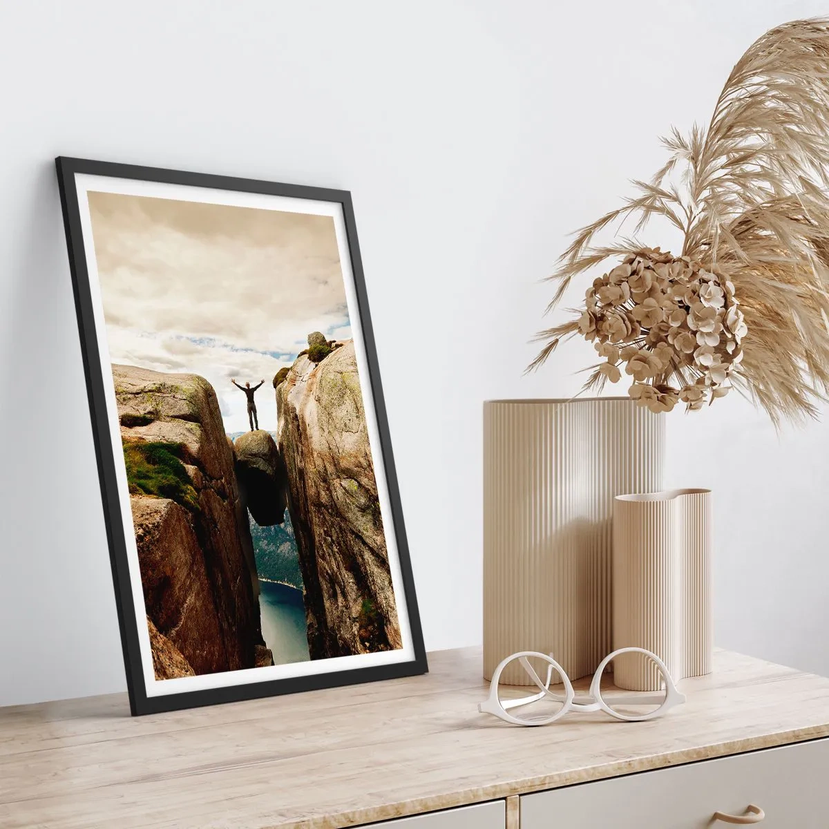 Plakat i sort ramme - En mand stående på en klippe ophængt mellem klipper - 50x70cm - Hvordan har jeg det! - Moderne vægdekoration til stue og soveværelse ARTTOR