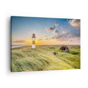 Lærredstryk - Billede på lærred - Et fyrtårn med enge og huse i solen i baggrunden - 70x50cm - Mellem bølgerne - Moderne vægdekoration til stue og soveværelse ARTTOR
