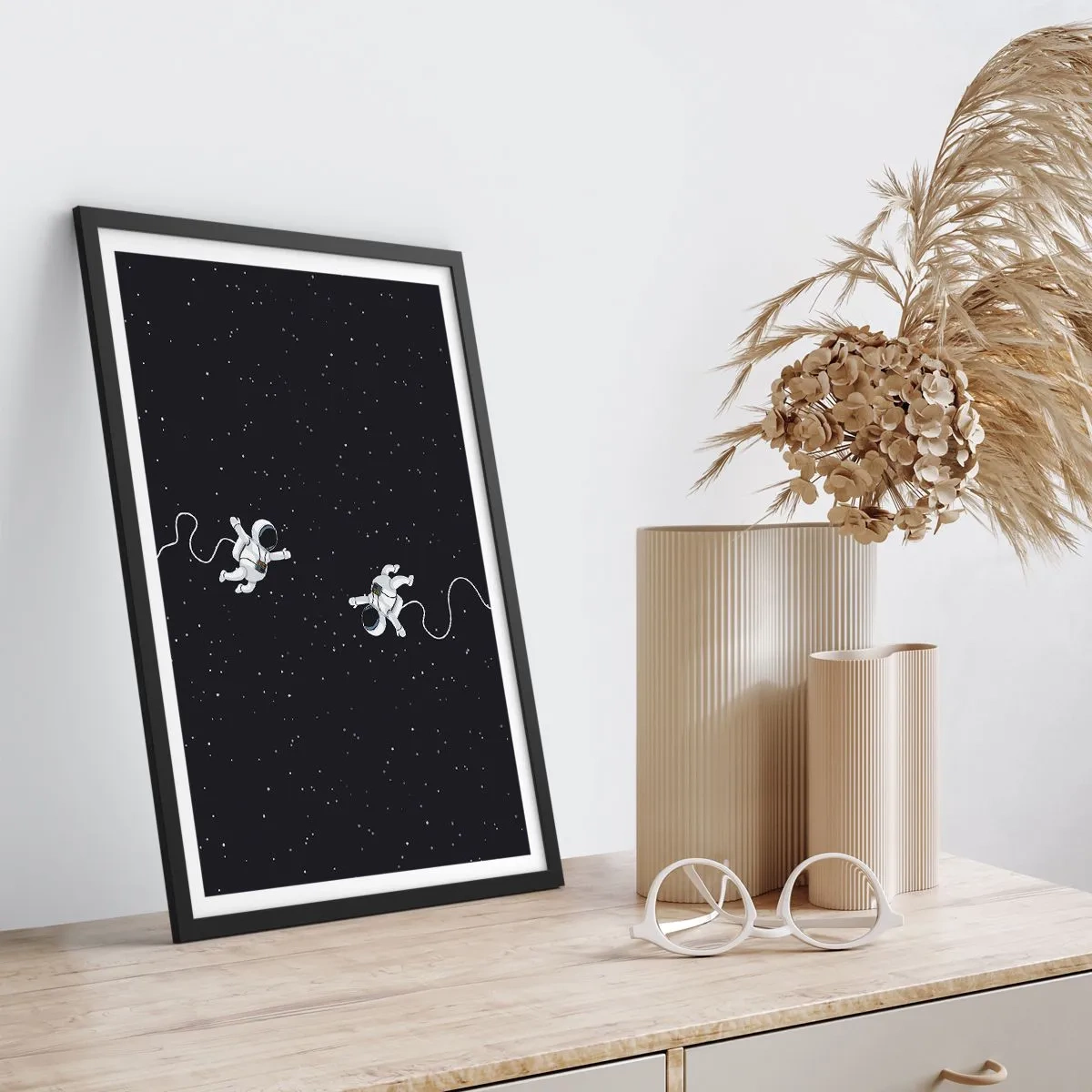 Plakat i sort ramme - To astronauter svæver i rummet - 50x70cm - Rummet vikler sig sammen - Moderne vægdekoration til stue og soveværelse ARTTOR