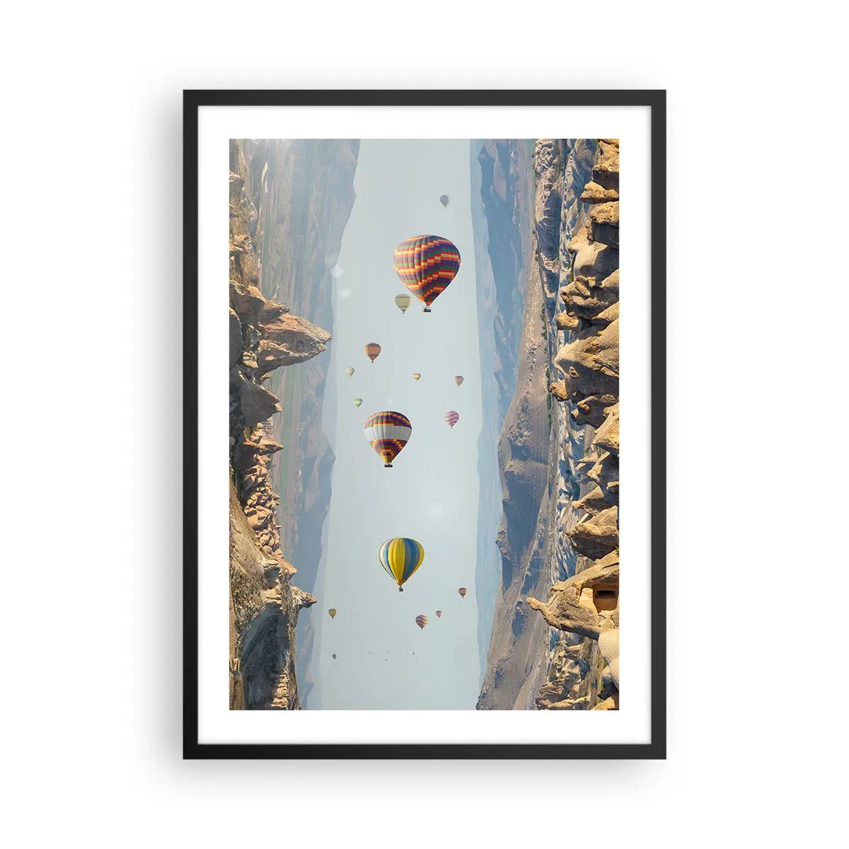 Plakat i sort ramme - Varmluftballoner svæver over klippefyldt terræn - 50x70cm - Alt er muligt her - Moderne vægdekoration til stue og soveværelse ARTTOR