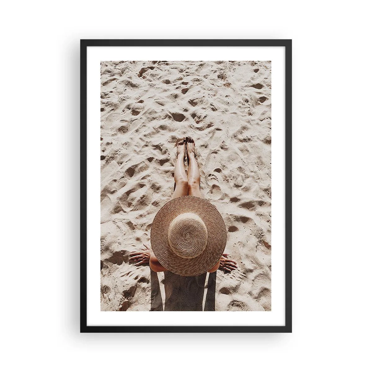 Plakat i sort ramme - Person solbader på stranden, set ovenfra med en stor hat mod sandet - 50x70cm - En drømmes tid - Moderne vægdekoration til stue og soveværelse ARTTOR